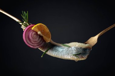 Limonlu ringa fileto, kırmızı soğan ve siyah arka planda biberiye..