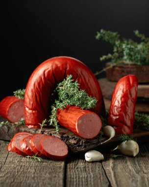 Smoked sausage with thyme and garlic on an old wooden table.