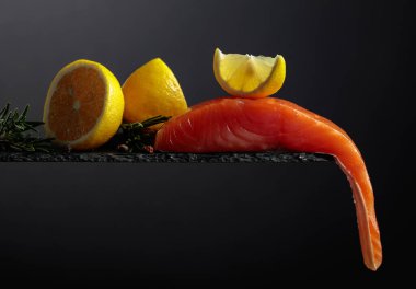 Smocked salmon with rosemary, lemon, and peppercorn on a black background. Copy space.