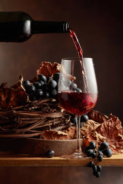 Wine is poured into a glass. Red wine and bunch of grapes.