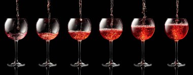 Siyah yansıtıcı arka planda bir bardağa pembe şarap dökülüyor..