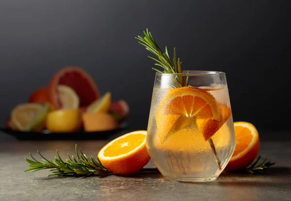 鸡尾酒杜松子酒汤加冰 迷迭香和橙子放在石桌上 背景是各种柑橘类水果 用来做鸡尾酒 — 图库照片