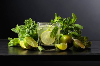Siyah ahşap bir masada buzlu, limonlu ve naneli mojito..