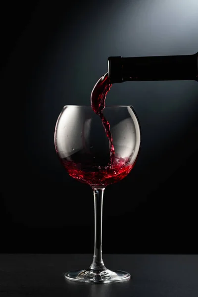 Rode Wijn Gieten Een Wijnglas Een Zwarte Achtergrond — Stockfoto