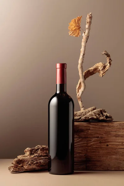 Bottle of red wine with a composition of old wood. Minimalistic composition with beige background for product branding, identity, and packaging. Copy space.