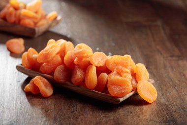 Ahşap bir tabakta kurumuş kayısılar, eski bir ahşap masada..