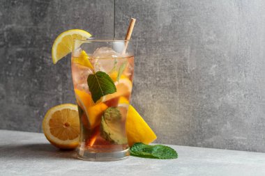 Buzlu çay, naneli ve limonlu. Gri arka planda malzemeleri olan soğuk, ferahlatıcı bir içecek. Boşluğu kopyala.