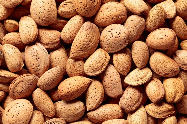 stock image Background of big raw unpeeled almonds situated arbitrarily. Top view.