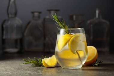 Bardaki taş bir masada buzlu, biberiyeli ve limonlu cin tonik.. 
