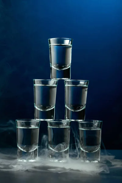 濃い青の背景に煙の中のウォッカのグラス クラブドリンクコンセプト — ストック写真