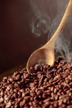 Orta pişmiş kahve çekirdekleri kızartma tavasında dumanlıdır. Boşluğu kopyala.