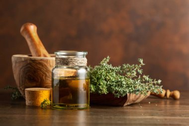 Eski ahşap bir masada taze kekik ile bir şişe kekik yağı. Boşluğu kopyala.