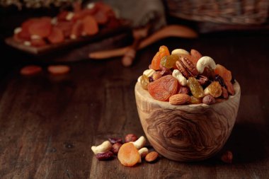 Kurutulmuş meyve ve çeşitli fındıklar eski ahşap bir masada..