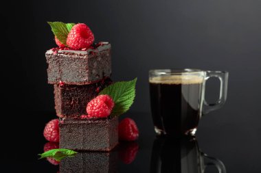 Taze ahududulu çikolatalı pasta ve siyah yansıtıcı arka planda sade kahve. Boşluğu kopyala.