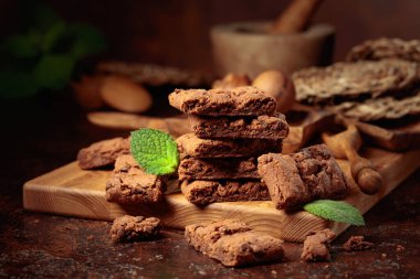 Pieces of fresh brownie with mint on an old table with kitchen utensils.