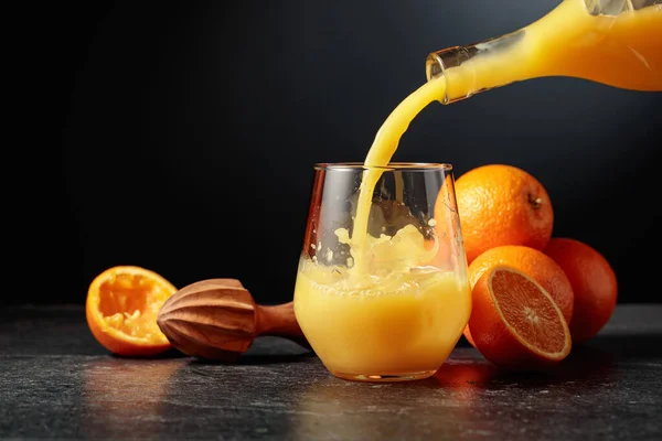 병에서 오렌지 주스를 얼음이 유리잔에 붓는다 — 스톡 사진