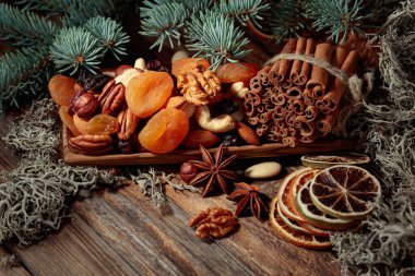 Eski ahşap bir masada kurumuş meyve ve fındık. Kurutulmuş turunçgiller, kayısılar, kuru üzümler, çeşitli fındıklar, tarçın çubukları ve anason içeren bir Noel..