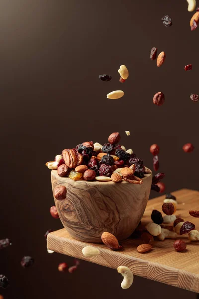 Flying dried fruits and nuts. The mix of nuts and dried berries are in a wooden bowl.  Copy space.