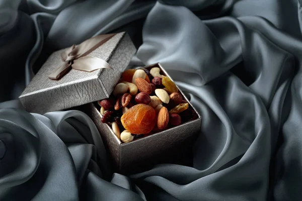 Dried fruits and nuts in a gift box on a grey cloth.