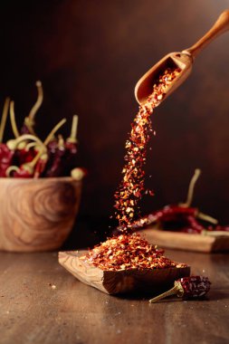 Biberler ahşap bir tabağa dökülür. Eski ahşap bir masada kırmızı biber ve kırmızı biber..