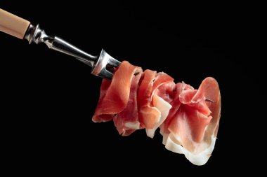 Bir çatalda ince dilim jambon. Siyah arkaplan.