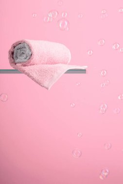 Towel on a glass shelf. Pink background with bubbles. Concept of the theme of bath and hygiene. Copy space.