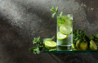 Buzlu, limonlu ve naneli mojito. Eski taştan bir arka planda sisli bir bardakta buzlu içecek. Boşluğu kopyala. 