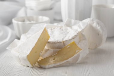 Beyaz ahşap bir masada beyaz çatal bıçaklı Camembert peyniri..