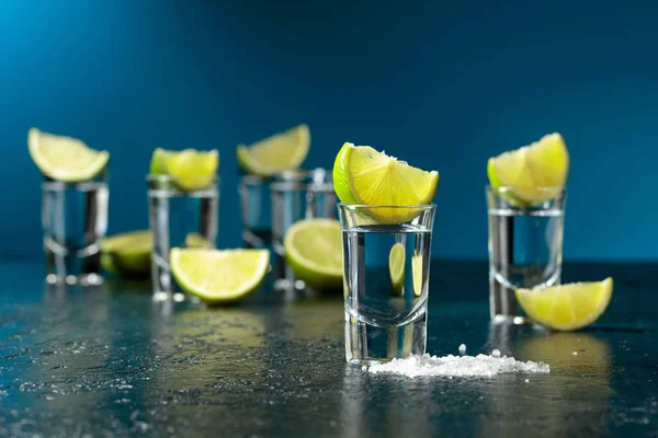 Tequila Shots Med Limeskivor Och Havssalt Ett Mörkblått Bord — Stockfoto