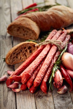 Eski ahşap bir masada soğan, sarımsak, biber ve biberiyeli füme sosis..
