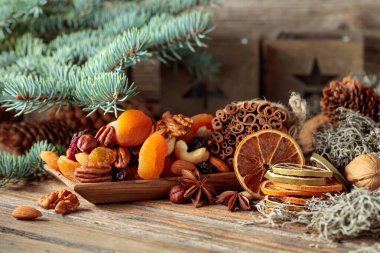 Eski ahşap bir masada kurumuş meyve ve fındık. Kurutulmuş turunçgiller, kayısılar, kuru üzümler, çeşitli fındıklar, tarçın çubukları ve anason içeren bir Noel..