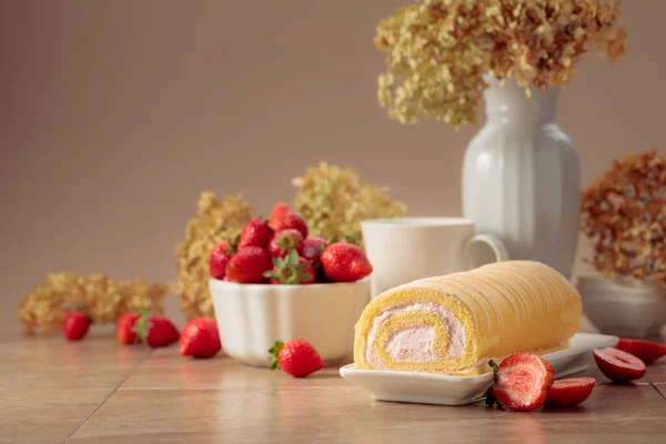 Homemade strawberry biscuit cake roll with cream cheese, whipped cream, and fresh berries. Delicious biscuit cake with strawberries on a beige background.