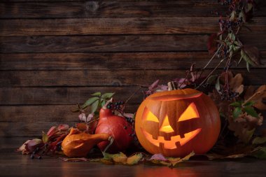 Kurumuş yapraklı balkabağı kafalı balkabağı feneri. Cadılar Bayramı sanat tasarımı, kutlama. Kavurucu mumla oyulmuş Cadılar Bayramı balkabağı.