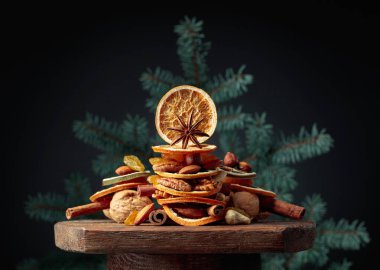 Eski ahşap bir masada kurumuş meyve ve fındık. Çam ağacından dalları olan bir Noel..