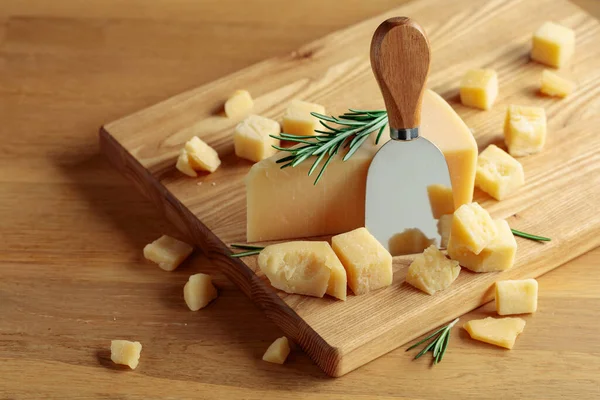 木のまな板にローズマリーとナイフでパルメザンチーズ — ストック写真