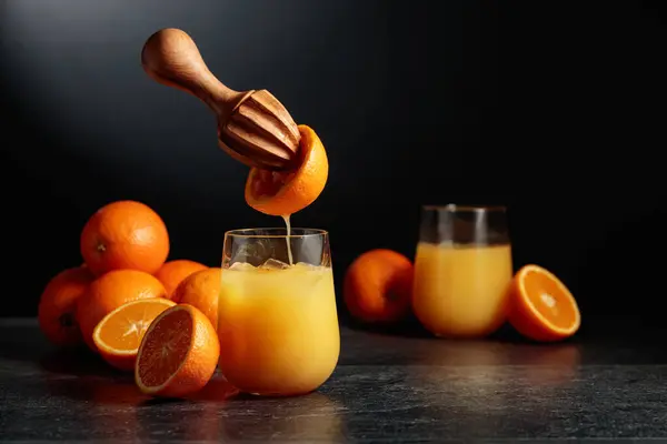 Orange juice is squeezed from fresh fruit. Juice is poured into a glass with ice. The concept of natural organic food.