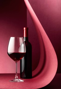 Kırmızı arka planda bir şişe kırmızı şarap. Boşluğu kopyala.