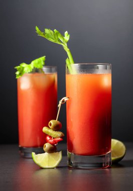 Kereviz, turşu, zeytin, limon ve kırmızı biberli Bloody Mary kokteyli. Siyah arka planda domates içeceği.