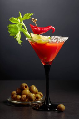 Kereviz, limon, kırmızı biber ve yeşil zeytinli Bloody Mary kokteyli. Cam deniz tuzu ile süslenmiş..