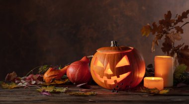 Kurumuş yapraklı balkabağı kafalı balkabağı feneri. Cadılar Bayramı sanat tasarımı, kutlama. Kavurucu mumla oyulmuş Cadılar Bayramı balkabağı.