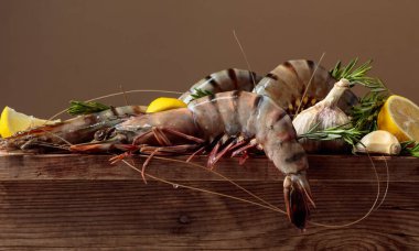 Eski ahşap bir masada limonlu, biberiyeli ve sarımsaklı taze kaplan karidesi. Boşluğu kopyala.