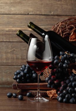 Red wine and blue grapes. Wine and grapes in a vintage setting on an old wooden table.