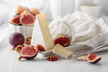 Beyaz ahşap bir masada incirli ve cevizli Camembert peyniri..