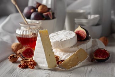 Beyaz ahşap bir masada incirli, cevizli ve ballı Camembert peyniri..