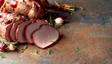 Mutfak masasında biberiyeli, sarımsaklı ve biberli füme jambon..