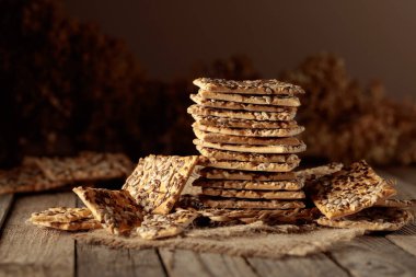 Eski ahşap bir masada ayçiçeği ve keten tohumlu çıtır krakerler. Basit sağlıklı yiyecekler. Boşluğu kopyala.