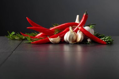 Kırmızı kırmızı biber, sarımsak ve biberiye siyah arka planda. Boşluğu kopyala..