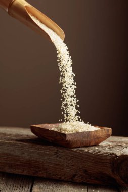 Tahta tabakta tahtadan bir kaşıkla beyaz susam taneleri dökülüyor. Boşluğu kopyala.