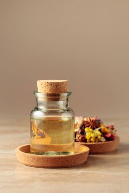 Temel yağ ya da küçük bir cam şişedeki bitkisel tentür. Bej bir arka planda kurutulmuş sağlıklı şifalı bitkiler ve şifalı bitkilerin karışımı. Boşluğu kopyala.