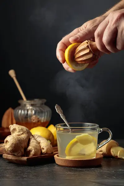 Ginger tea with lemon and honey. Juice is squeezed out of a lemon with an old wooden juicer.